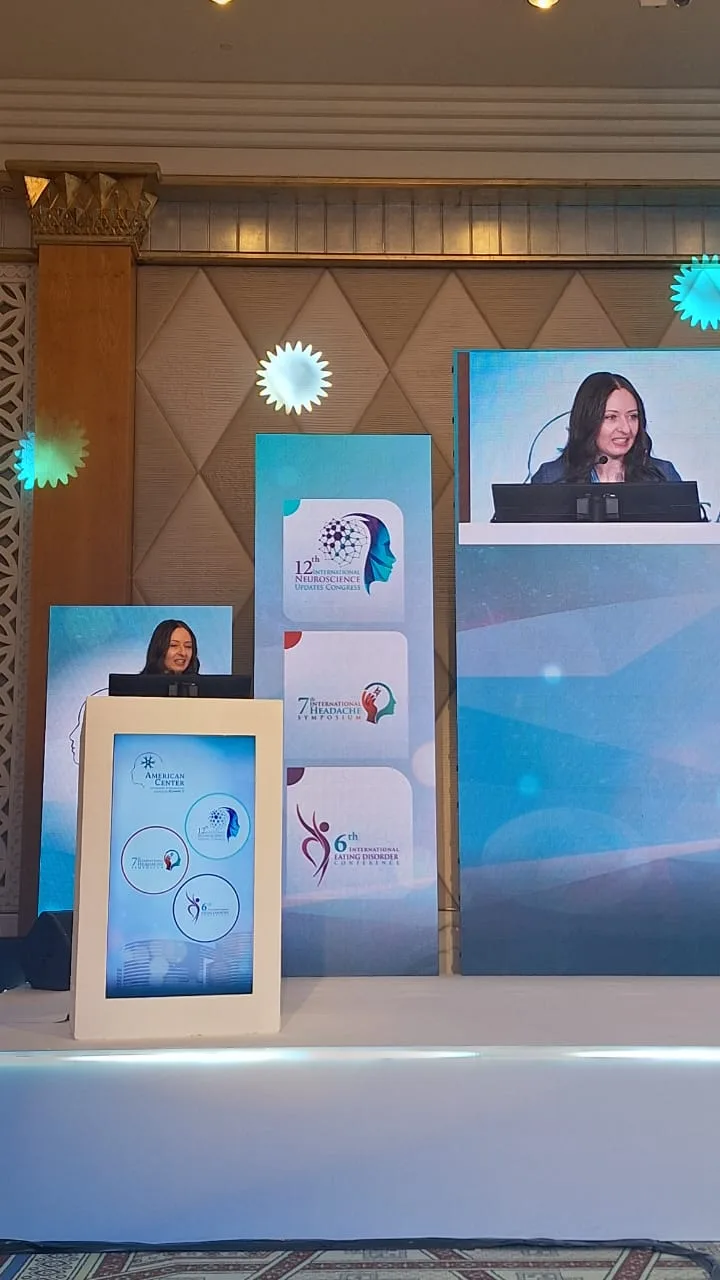متحدثة على منصة مؤتمر دولي بدبي مع عرض مباشر على الشاشة